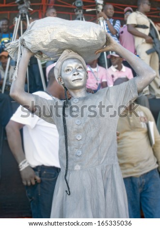 CAP-HAITIEN, HAITI - NOV 18,  Unidentified Haitian woman painted in silver waiting for the president visit with life improvement expectations on November 18, 2013 in Cap-Haitien, Haiti