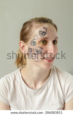 Smiling young blond girl with face painting Roses