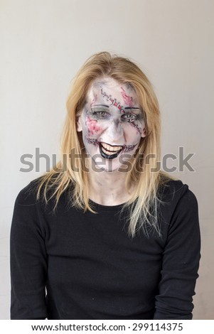 Attractive young blond girl with halloween zombie face painting