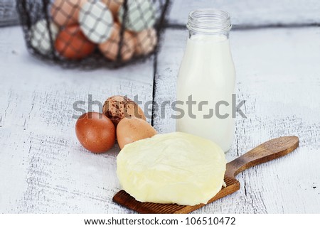 Farm fresh milk, butter, and eggs against a rustic background. Milk is in a vintage glass milk bottle. Shallow depth of field.