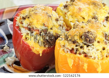 Three colorful baked stuffed peppers with beef, rice, vegetables and cheese.