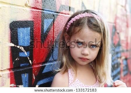 Worried little girl in an urban setting looking into the camera.