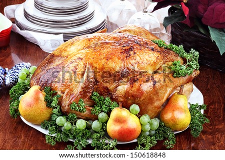 Thanksgiving Or Christmas Turkey Dinner With Fresh Pears, Grapes And Parsley. Poinsettia Flower Arrangement, Dishes And Wine Glasses In Background.