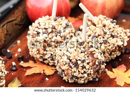 Apples dipped in caramel, chocolate chips and nuts with autumn leaves.