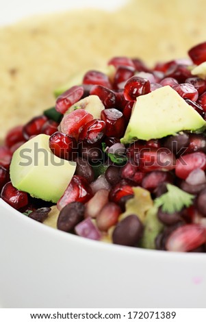 A healthy relish or salsa with pomegranate, avocado, red onions, black beans and cilantro served with corn chips.