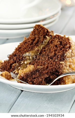 A slice of German chocolate cake on a plate. Shallow depth of field with selective focus on bite on the fork.