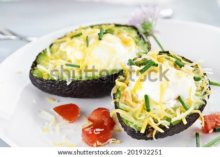 Eggs with cheddar cheese baked in fresh avocados and garnished with chives. Extreme shallow depth of field.
