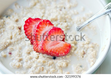 Macro of a bowl of hot oatmeal with fresh strawberries cut into the shapes of hearts for a heart healthy breakfast.