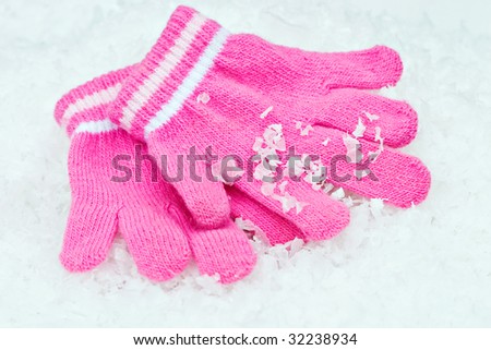 Little girl\'s pink winter gloves lying in the snow