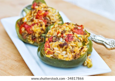 Baked peppers stuffed with turkey burger, rice, tomatoes and cheddar cheese. Shallow DOF with focus on pepper in front.
