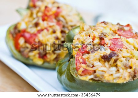 Macro of baked peppers stuffed with turkey burger, rice, tomatoes and cheddar cheese. Shallow DOF with focus on pepper in front.