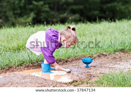 Cute little girl playing in the mud with ice cream scoops.