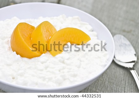 Cottage cheese and peaches in a white bowl on a rustic background.