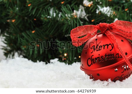 Beautiful red Christmas bell ornament lies in the snow with copyspace and a message of \