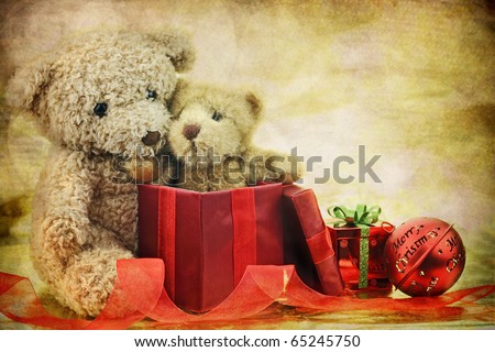 An old antique teddy bear hugs his Christmas gift, a new little teddy bear friend, while surrounded by ornaments and ribbons . Copy space available.
