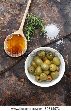 Spanish olives with olive oil, rosemary, sea salt and olive on a rustic slate background.