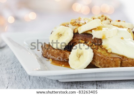 French toast topped with sliced bananas, nuts, cream cheese sauce and ...