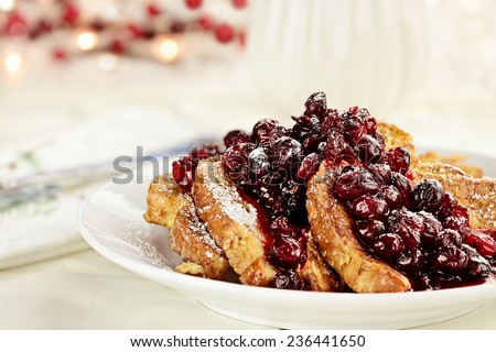 Cranberry sauce made with maple syrup, butter and fresh cranberries over delicious golden french toast for Christmas morning. Extreme shallow depth of field with selective on foreground.