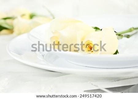 Romantic table setting with long stem yellow rose. Shallow depth of field.