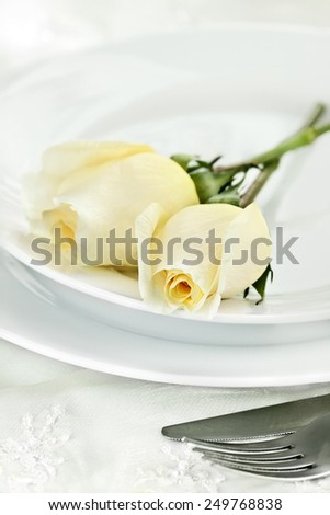 Romantic table setting with long stem yellow roses. Extreme shallow depth of field with selective focus on rose in foreground.