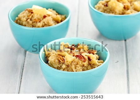 Three bowls of cooked quinoa with pecans, apples, and maple syrup with shallow depth of field.