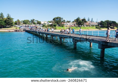 Cowes, Australia - March 8, 2015: children diving off Cowes Pier at Phillip Island, a popular family holiday destination.