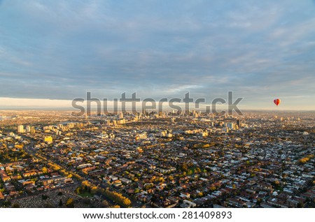 A hot air balloon floating above the urban sprawl of Melbourne, Australia in the light of a spring dawn.