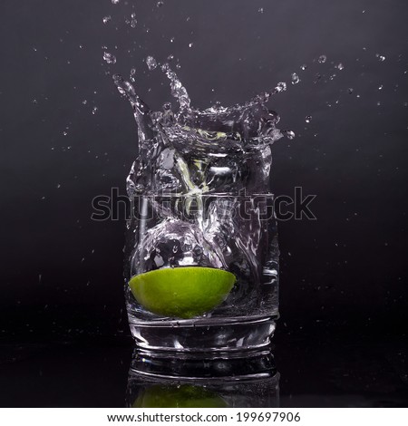 Splashes of water, lemon falling into a glass, isolated, reflection, white background