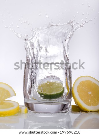 Splashes of water, lemon falling into a glass, isolated, reflection, white background