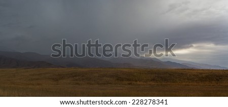 Yellow field, mountain, storm clouds, panorama