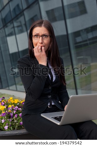 Frightened and stressed beautiful business woman biting her fingers