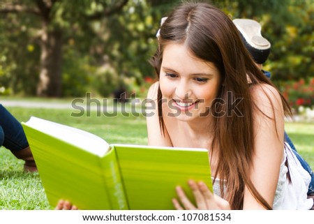 Portrait of a young beautiful woman reading a book in the park