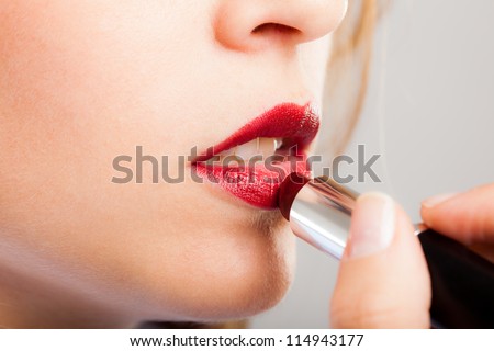 Portrait of a gorgeous woman applying lipstick