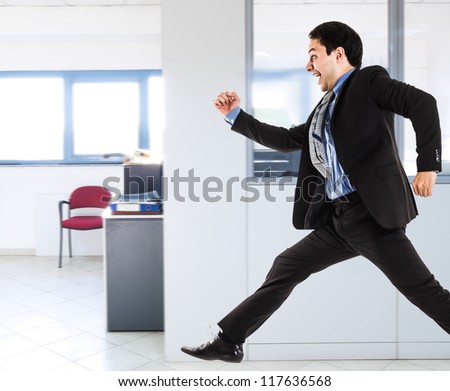 Portrait of an active businessman running in his office
