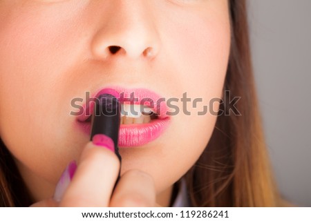 Portrait of a gorgeous woman applying lipstick