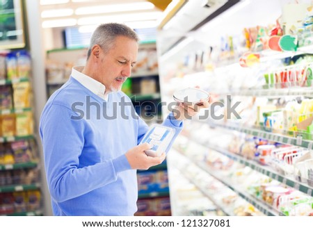 Man Comparing Products At The Supermarket