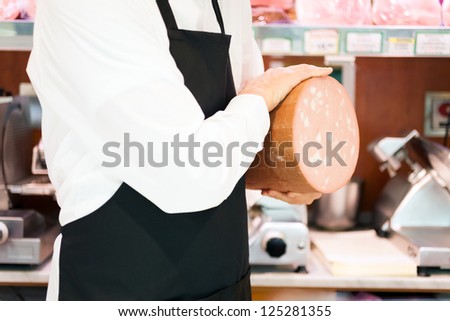 Shopkeeper showing a bologna in an italian grocery store