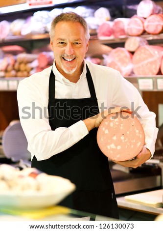 Shopkeeper showing mortadella in an italian grocery store