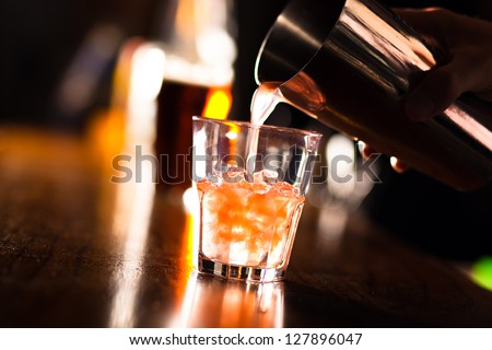 Barman pouring a cocktail into a glass
