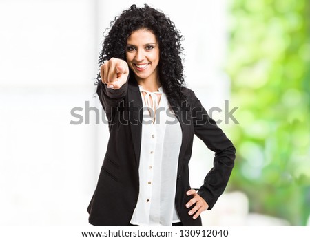 Portrait of a smiling beautiful woman pointing her finger at you