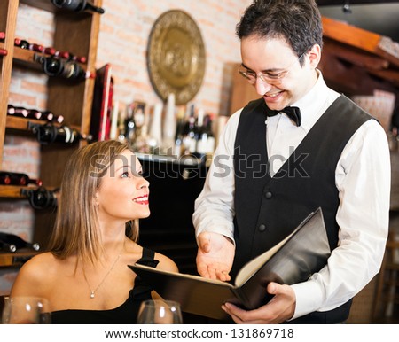 Waiter suggesting food to a woman in a restaurant