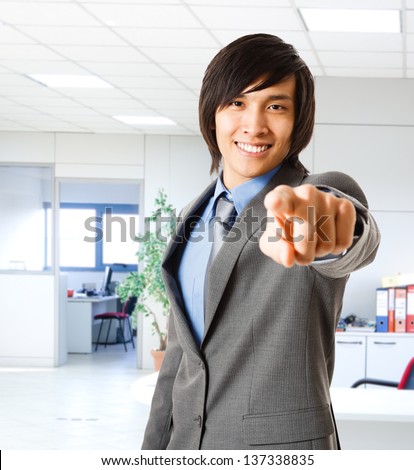Portrait of a smiling asian businessman pointing his finger at you