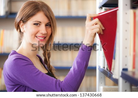Portrait of a student taking a book from a bookshelf