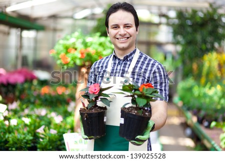 Happy gardener in a greenhouse holding flowers