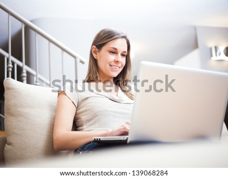 Woman using a laptop while relaxing on the couch