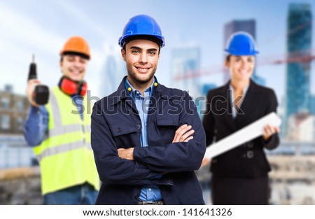Three workers in front of a construction site
