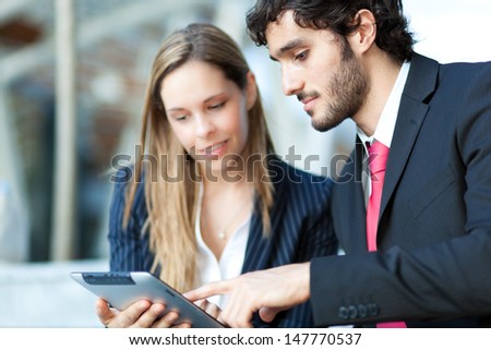 Two business people looking at a tablet in an urban setting