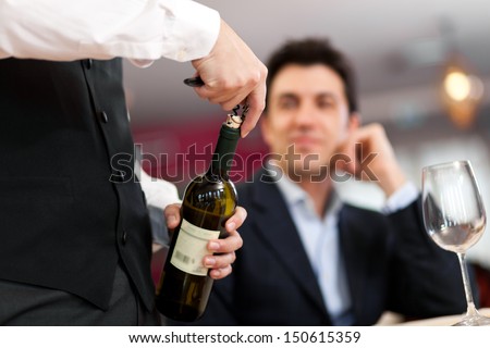 Waiter Serving Wine To A Customer At The Restaurant
