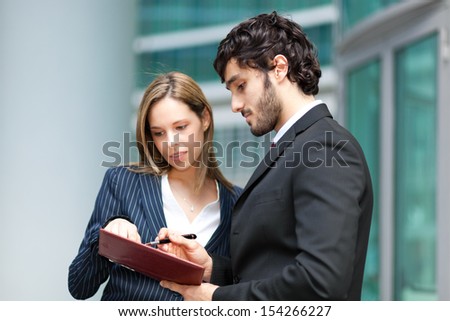 Two business people consulting an agenda