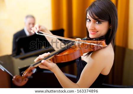 Woman playing the violin with a pianist